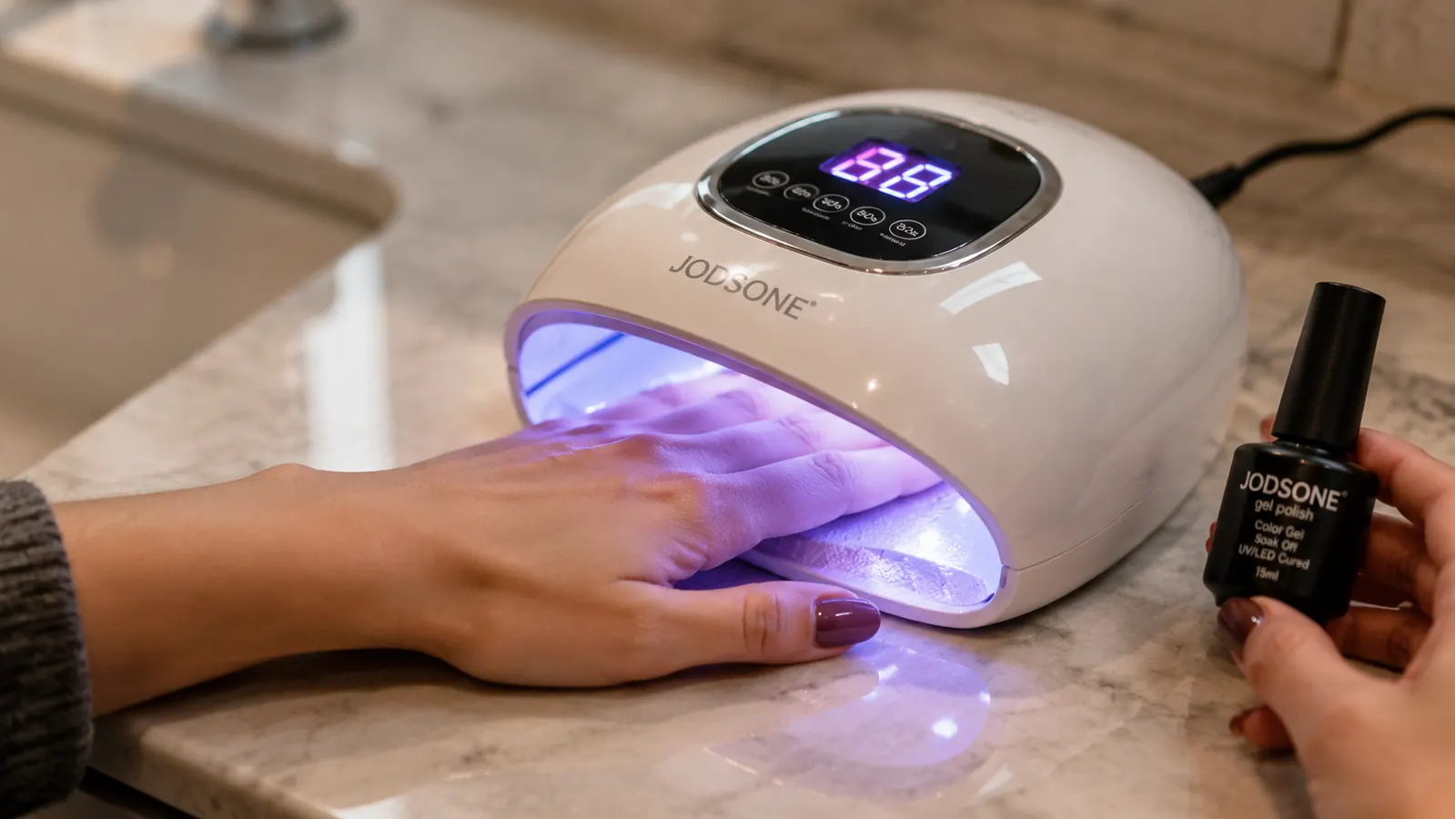 Hand curing gel polish under a UV lamp from the JODSONE kit