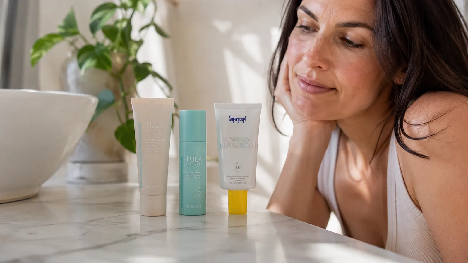 Bathroom counter with a gentle cleanser, moisturizer, and mineral sunscreen lined up as a simplified skincare routine
