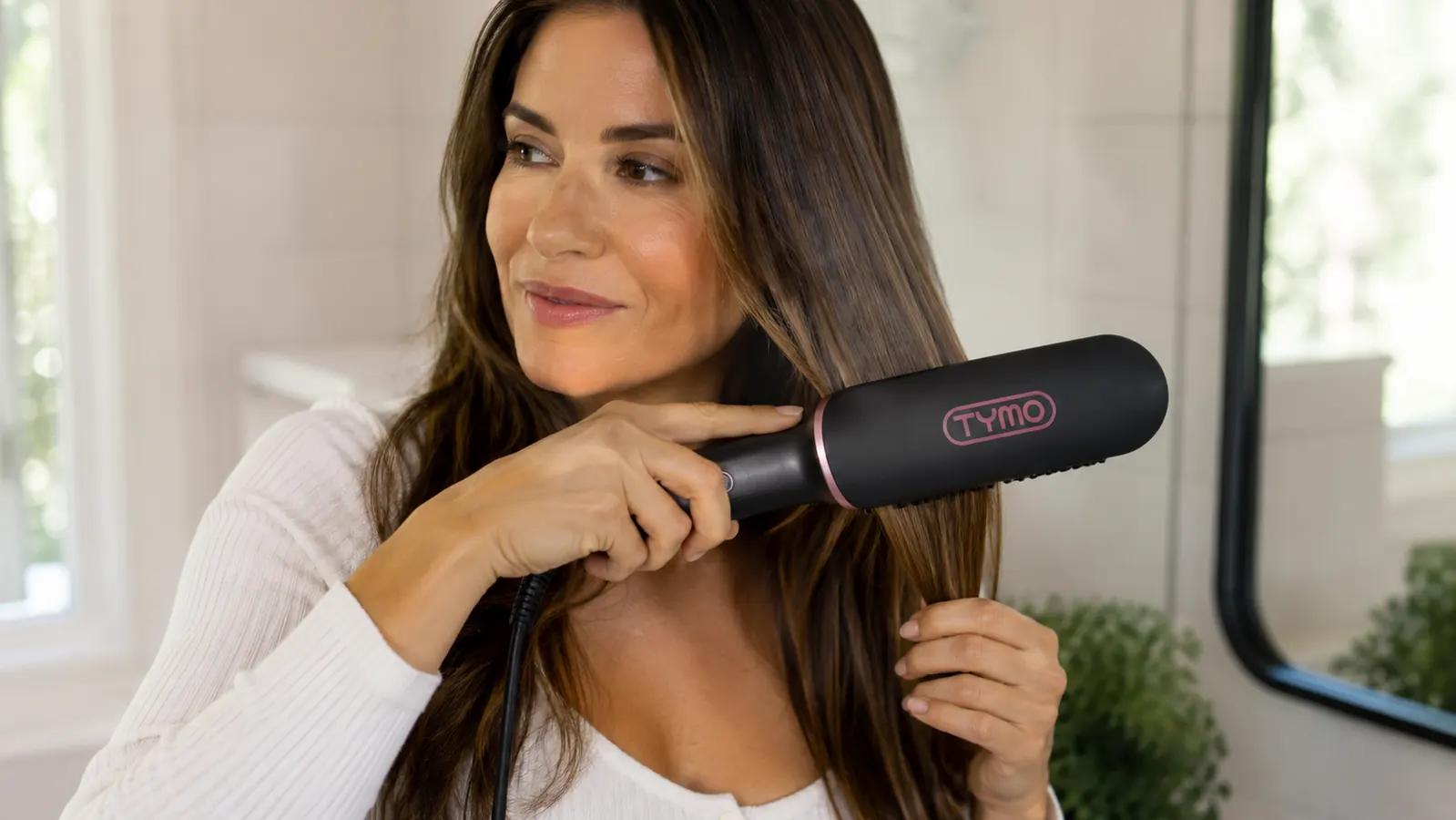 Close-up of the TYMO straightener brush bristles gliding through a section of hair, showing the ceramic plate detail