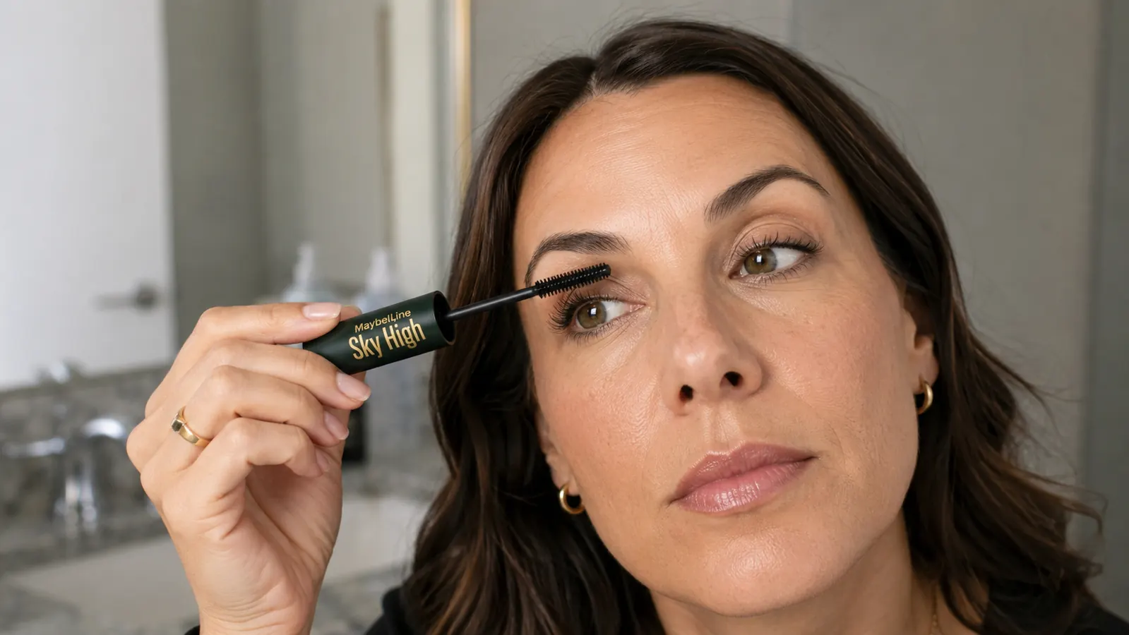 Hand holding the Maybelline Sky High mascara wand angled toward the camera showing the bristle texture